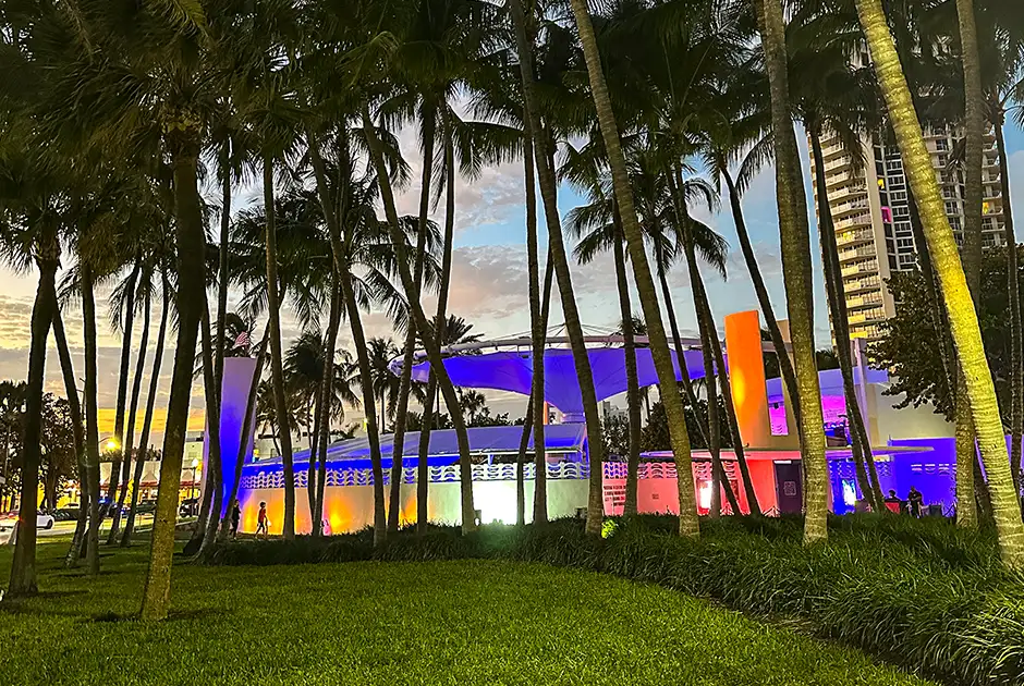 Miami Beach Bandshell lit up at dusk among palm trees