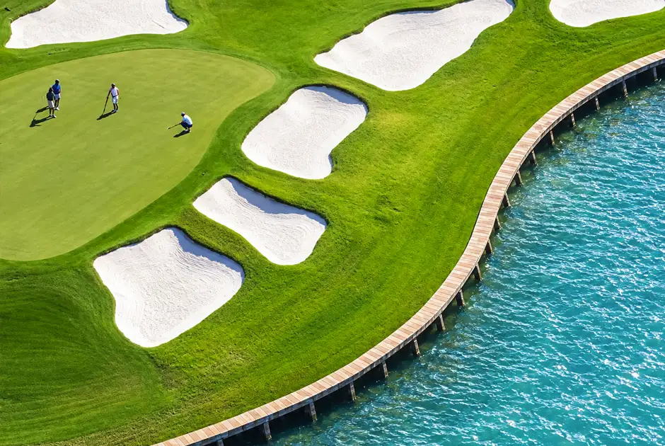 Aerial view of a golf course with sand bunkers along the water